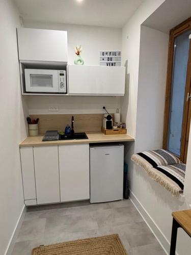 une petite cuisine avec des armoires blanches et un micro-ondes dans l'établissement Studio O Fil du Vent, à Gruissan
