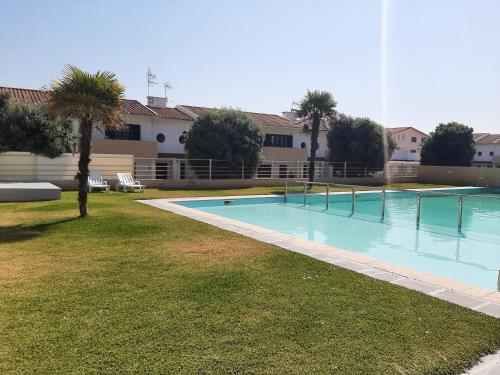 a swimming pool in a yard with palm trees at Swim&Beach Condominio Torreira in Torreira