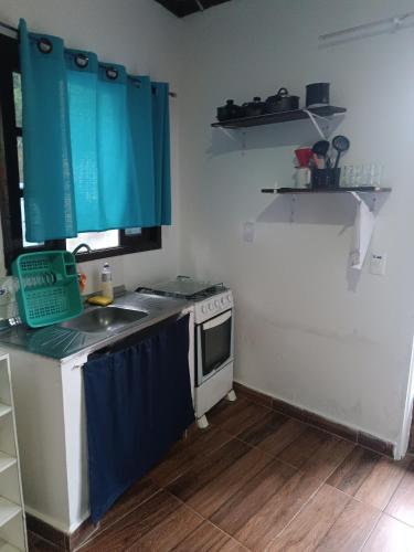a small kitchen with a sink and a stove at SUITES E CHALES PRIVADOS Rock's&Rose's home in Camburi