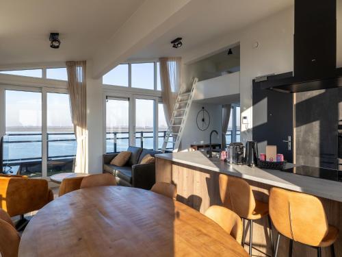 a kitchen and living room with a wooden table and chairs at Penthouse in Sint-Annaland by the Beach in Sint Annaland