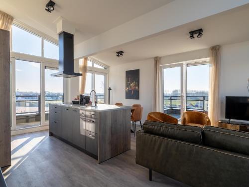a living room with a couch and a kitchen with windows at Penthouse in Sint-Annaland by the Beach in Sint Annaland