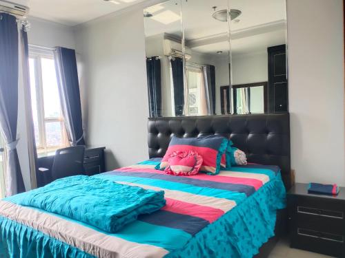 una camera da letto con un letto con un grande specchio di Sewa Apartemen Thamrin Residences a Giacarta
