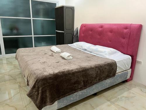 a bed with a pink headboard and two towels on it at Kiliog Valley Inn in Tagiptip