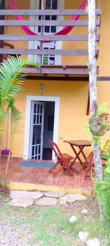 a wooden deck with a table and chairs in front of a building at SUITES E CHALES PRIVADOS Rock's&Rose's home in Camburi