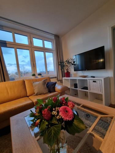 a living room with a couch and a table with flowers at Villa Schönfeld Wohnung 7 in Papenburg