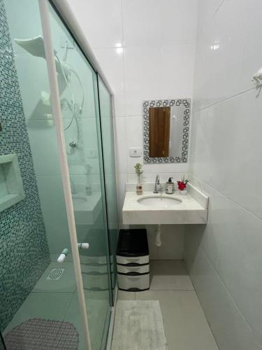 a bathroom with a sink and a glass shower at Chácara Gomes - Caiubura - Bertioga in Bertioga
