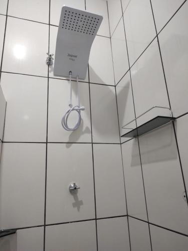 a white tiled bathroom with a shower at Hospedagem aconchego in Pardinho