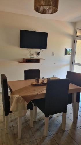 a dining room table and chairs with a table and a television at Brisas Rumipal dúplex premium Villa Rumipal in Villa Rumipal