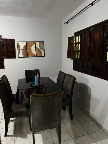 a dining room with a black table and chairs at Hospedagem dos Belos in São José da Coroa Grande