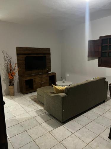 a living room with a couch and a television at Hospedagem dos Belos in São José da Coroa Grande