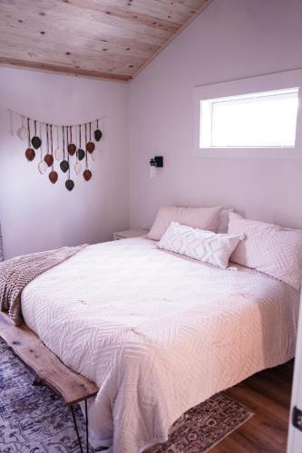 a bedroom with a bed with white sheets and a window at Treehouse Acres in Elkhart
