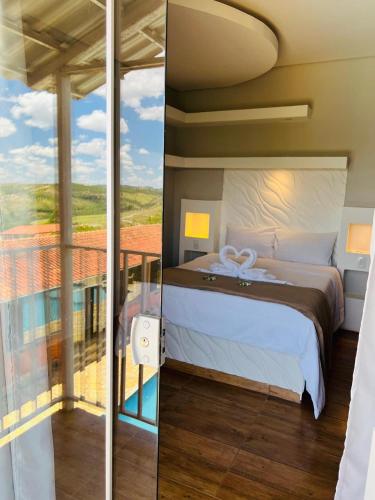 a bedroom with a bed and a balcony with a view at Pousada Hilário ltda in São João del Rei