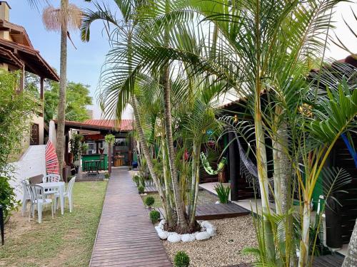 un giardino con palme e un vialetto in legno di Hospedaria aconchego 4 a Garopaba
