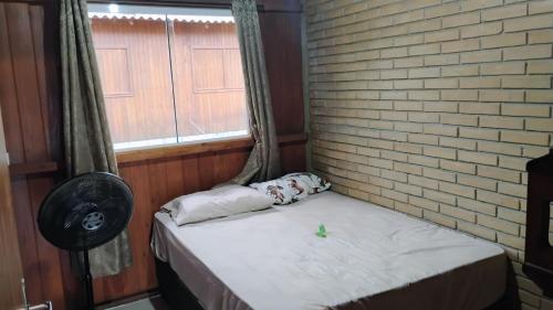 a small bed in a room with a brick wall at Casa Sítio Campo e Mar Balneário Picarras in Piçarras