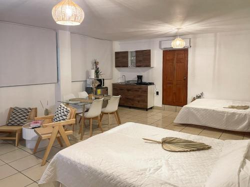 a bedroom with two beds and a table and a kitchen at Kaia Loft in La Libertad