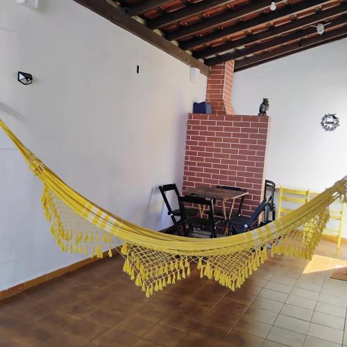 a hammock in a room with a table and chairs at Aconchego pé na areia in Praia Grande
