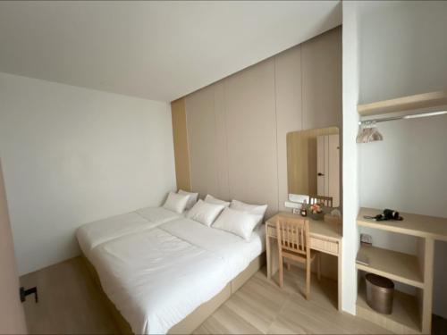 a small bedroom with a white bed and a desk at Sri House at Supasarnrangsan in Hat Yai