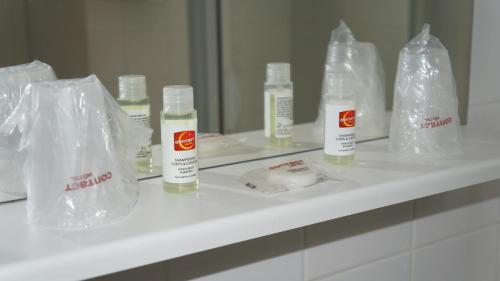 a bathroom counter with bottles of lotion in plastic bags at Hôtel Robinson in Auch