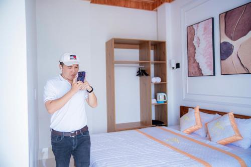 a man taking a picture of a bedroom with a bed at Khách Sạn Bình Minh-Đảo Phú Quý in Cu Lao Thu