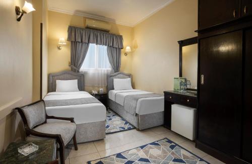 a hotel room with two beds and a chair at Holidays Express Hotel in Cairo