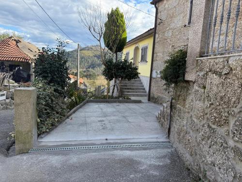 a driveway leading to a yellow house with stairs at Moradia do Pátio in Arcos de Valdevez