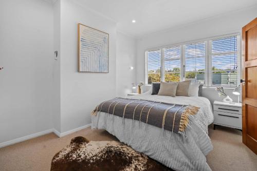 a white bedroom with a bed and a window at Elegant Hamilton East Home Near Gardens and Cafes in Hamilton