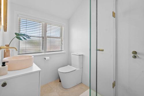 a white bathroom with a toilet and a sink at Elegant Hamilton East Home Near Gardens and Cafes in Hamilton