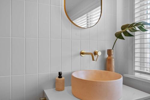 a bathroom with a bowl sink and a mirror at Elegant Hamilton East Home Near Gardens and Cafes in Hamilton