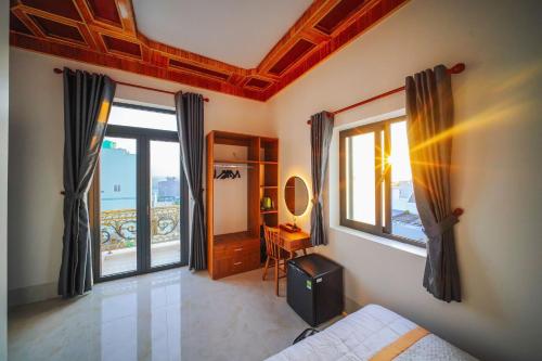 a bedroom with a bed and windows and a desk at Khách Sạn Bình Minh-Đảo Phú Quý in Cu Lao Thu