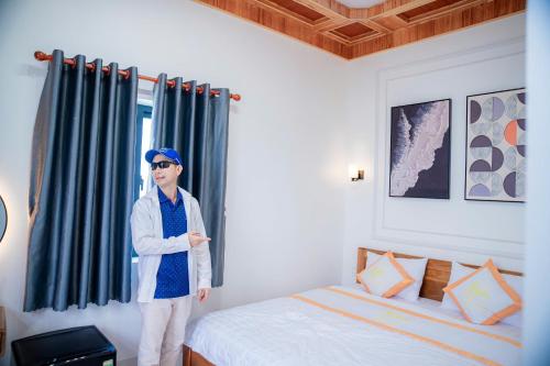 a man standing in a bedroom with a bed at Khách Sạn Bình Minh-Đảo Phú Quý in Cu Lao Thu