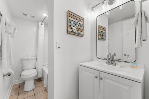 a bathroom with a toilet and a sink and a mirror at Serenity at A-521 in Panama City Beach