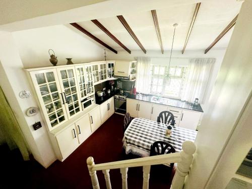 kuchnia z białymi szafkami i stołem w obiekcie Two-room cottage kandy w mieście Kandy