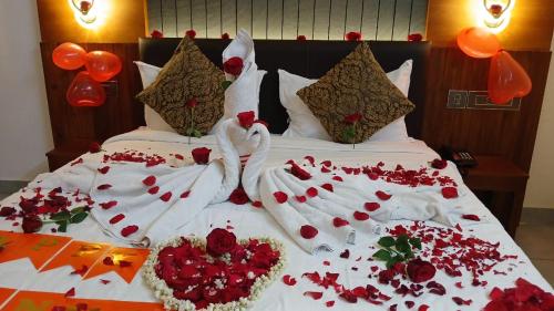 a bed with two people dressed in white with flowers on it at Silverstone Inn in Nedumbassery