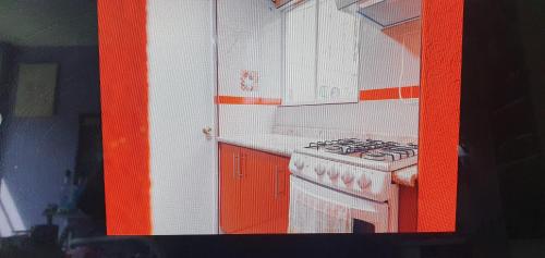 an orange and white kitchen with a stove and cabinets at Espacio de susymario in Mexico City