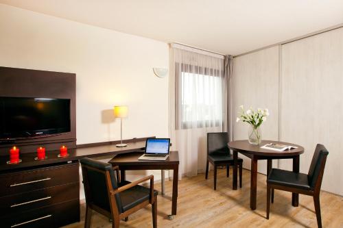 a living room with a table and chairs and a laptop at Residhome Toulouse Tolosa in Toulouse