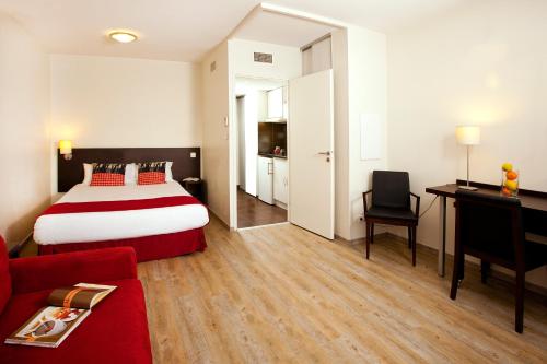 um quarto de hotel com uma cama e um sofá vermelho em Residhome Toulouse Tolosa em Toulouse