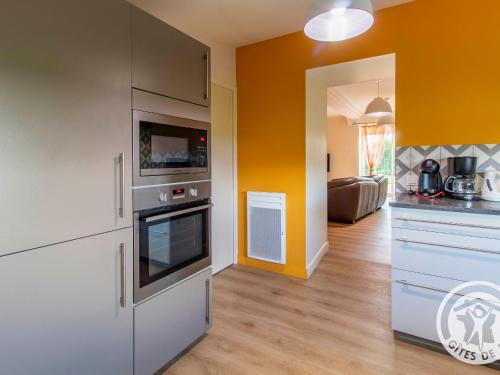 - une cuisine avec des placards blancs et un mur orange dans l'établissement Gîte Camomille à la campagne, proche du Puy du Fou - FR-1-622-99, à Saint-Georges-du-Puy-de-la-Garde