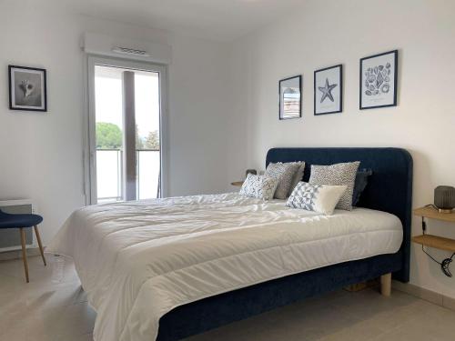 une chambre avec un grand lit avec une tête de lit bleue dans l'établissement Bel appartement T2 avec terrasse privative et parking à Balaruc-les-Bains - FR-1-553-299, à Balaruc-les-Bains
