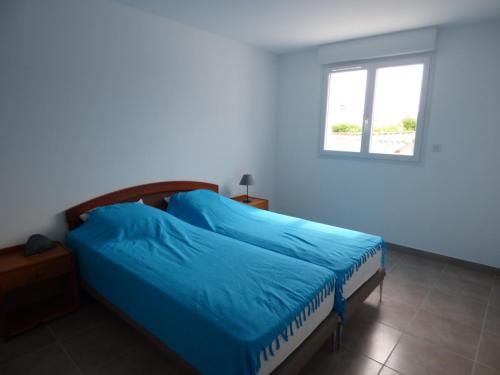 une chambre avec un lit bleu avec une fenêtre dans l'établissement Appartement climatisé avec parking, proche mer, pour 4 pers. - FR-1-475-199, à Saintes-Maries-de-la-Mer