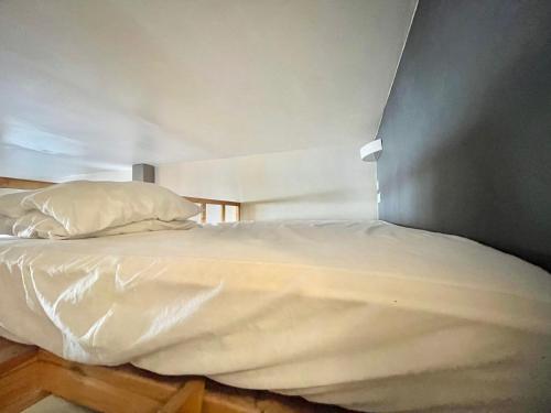 un lit avec des draps blancs et des oreillers dans une chambre dans l'établissement Studio spacieux en centre-ville avec piscine - FR-1-716-80, à La Grande Motte