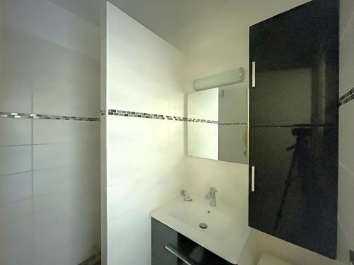 une salle de bain blanche avec un lavabo et un miroir dans l'établissement Appartement 4 pers, terrasse, parking - FR-1-475-192, à Saintes-Maries-de-la-Mer