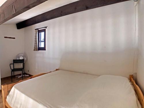 un lit blanc dans une chambre avec une fenêtre dans l'établissement Appartement 4 pers. avec mezzanine et balcon, stationnement privatif - FR-1-475-194, à Saintes-Maries-de-la-Mer