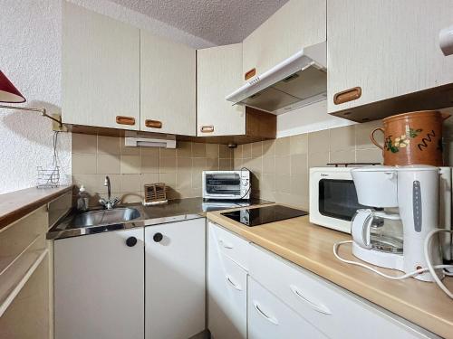 une cuisine avec des armoires blanches et un micro-ondes dans l'établissement Studio pour 4 Pers., Climatisé, Animaux Bienvenus - FR-1-475-207, à Saintes-Maries-de-la-Mer