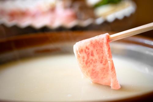 a piece of meat on a wooden spoon in a bowl of milk at Wataya Besso in Ureshino