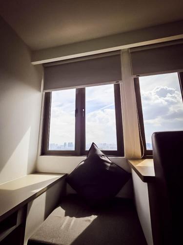 a room with two large windows and a pillow at Riveria City by Nomadnest in Kuala Lumpur