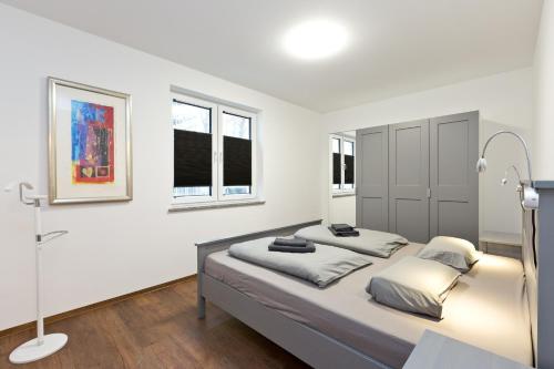 a white bedroom with a bed and two windows at Am Hafen1 in Röbel