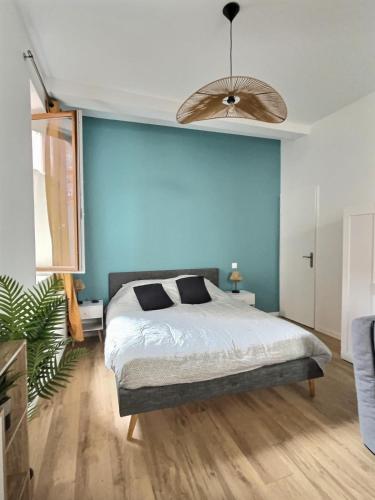 une chambre avec un grand lit et un mur bleu dans l'établissement Esprit Cosy - Coeur de Village, à Nègrepelisse