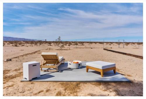 a chair and a bench in the middle of the desert at Desert Dream Cabin, Healing Mineral Water Tub in Twentynine Palms