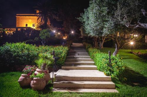 a stone path in a garden at night at Hotel Foresteria Baglio Della Luna in San Leone