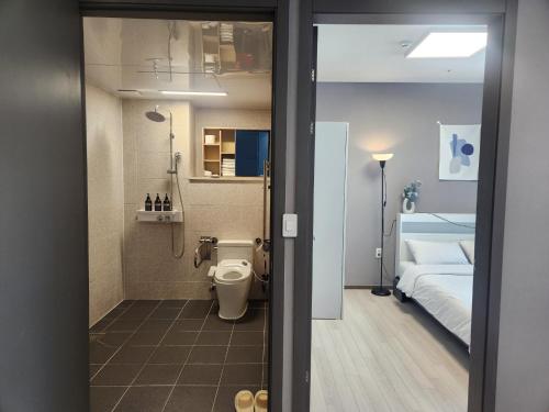 a bathroom with a toilet and a bedroom with a bed at Brand New Residence with Family in Busan